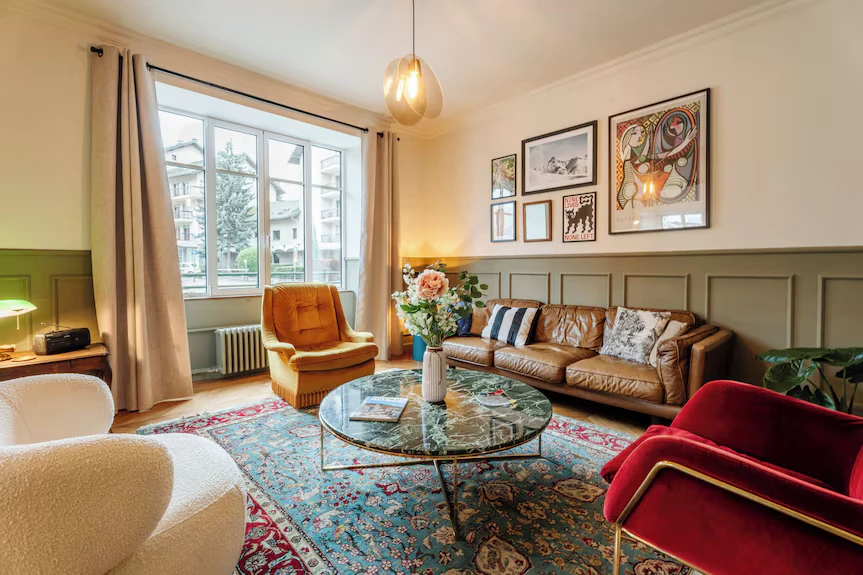 Le salon du Falcoz : canapé en cuir, fauteuil de velours rouge, table en marbre et affiches au mur